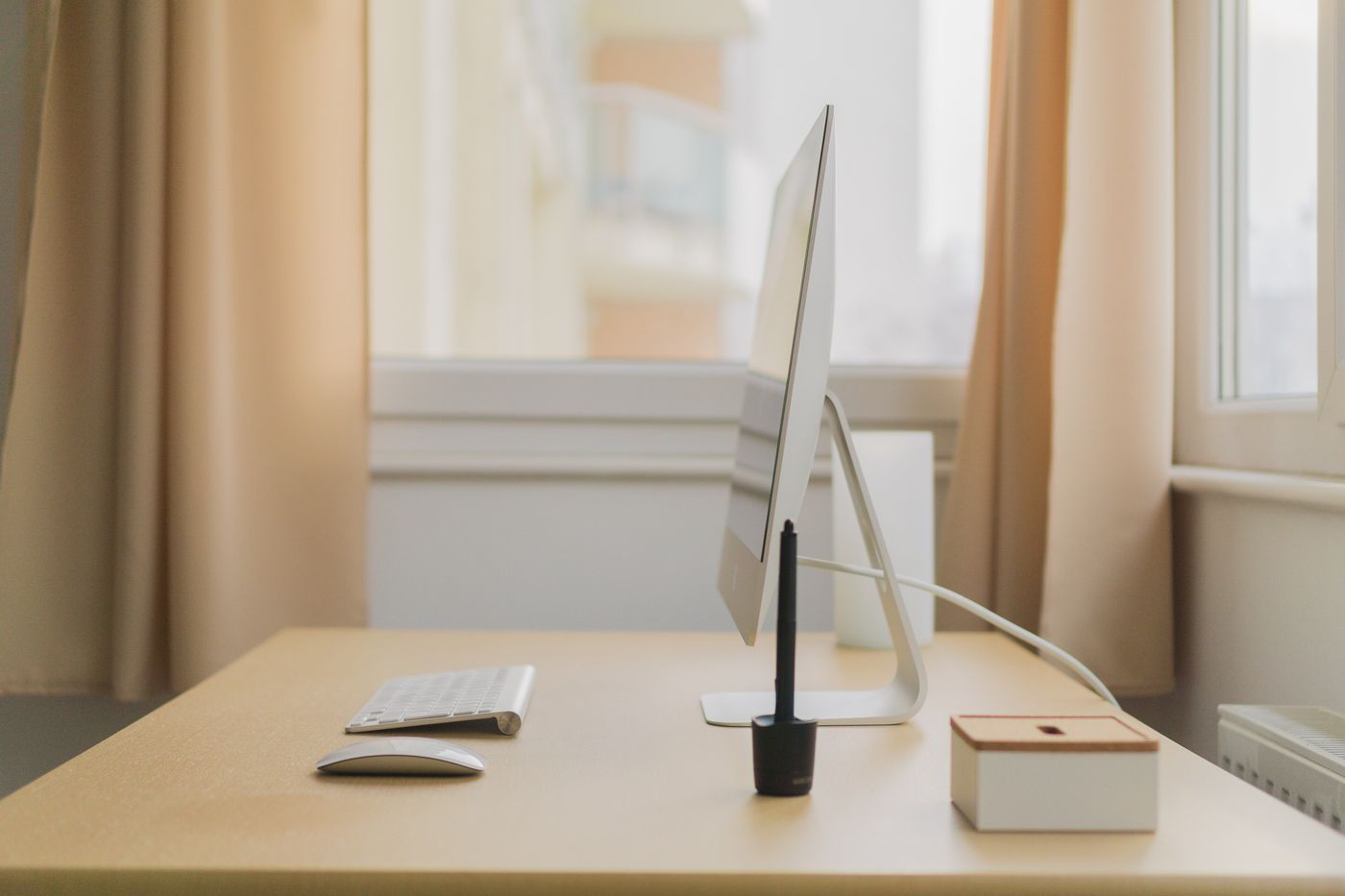 A desk by a window with a screen, a keyboard and daylight